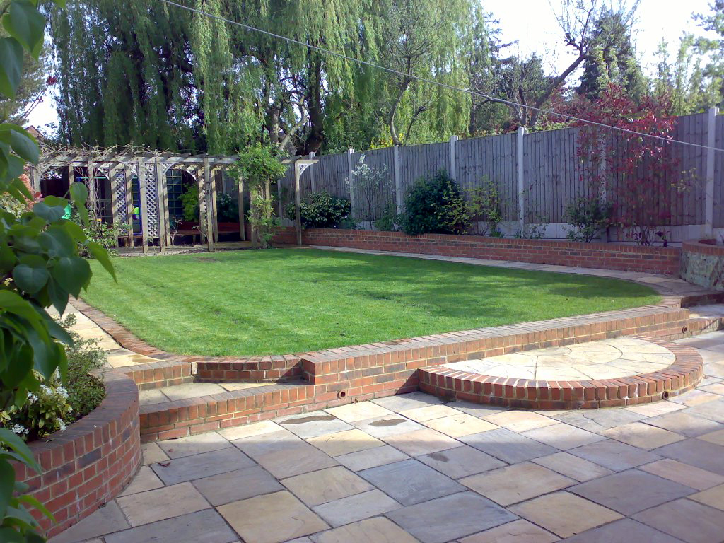 Formal garden with pergola in front of lawn under weeping willow
